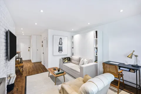 a living room with furniture a flat screen tv and a refrigerator