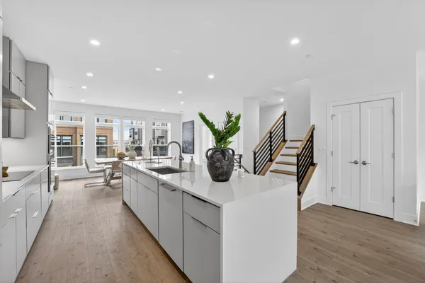 a large white kitchen with stainless steel appliances kitchen island granite countertop a large counter top and a stove