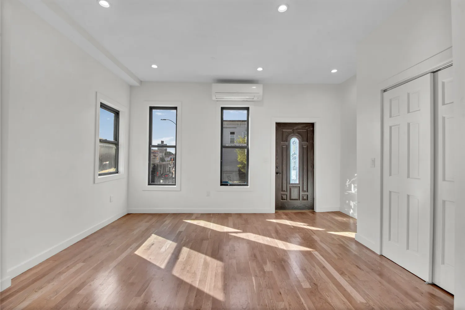 a view of an empty room with wooden floor and a window