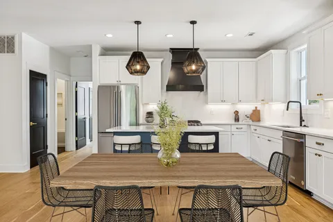 a kitchen with stainless steel appliances granite countertop a kitchen island a stove a table and chairs