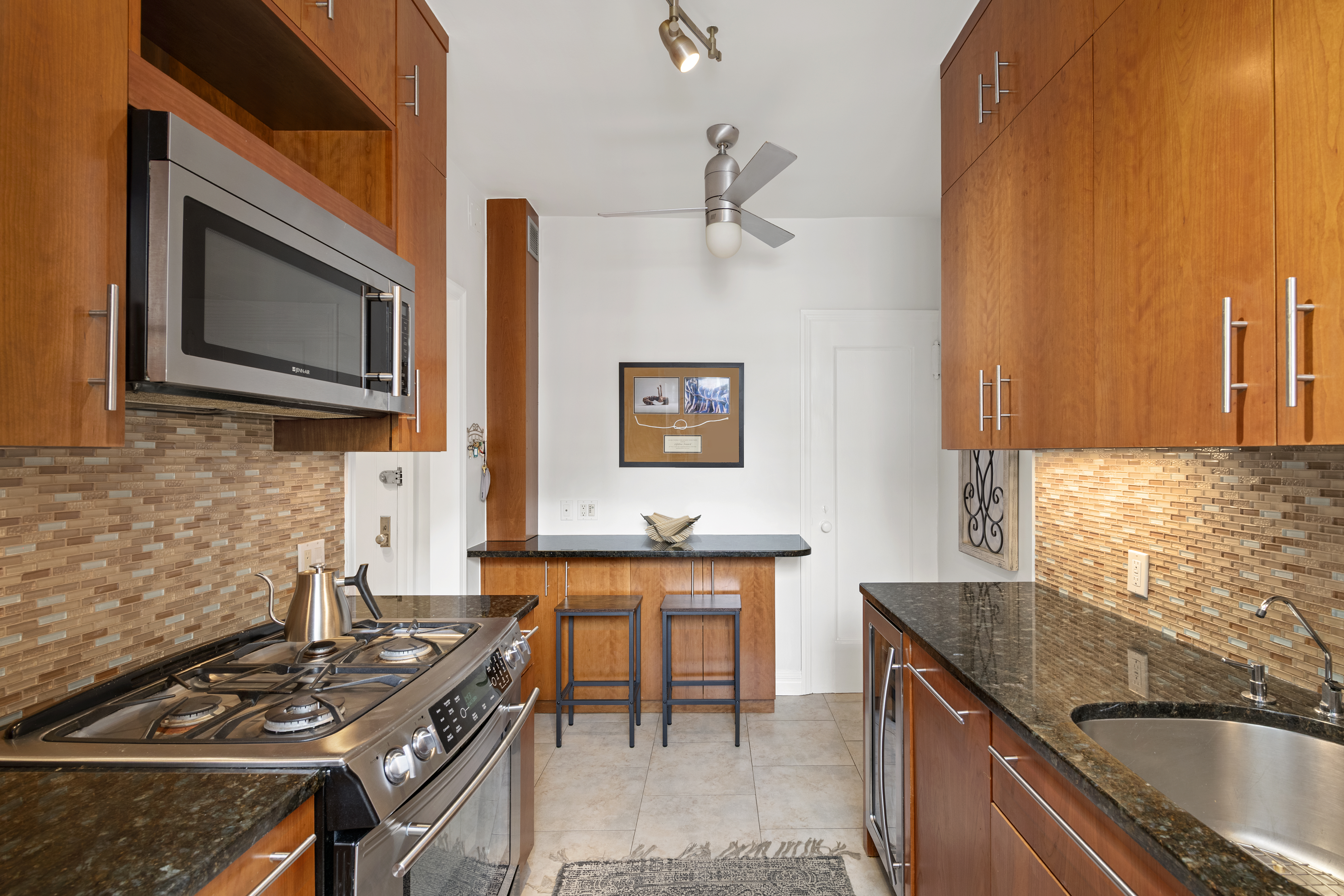 222 East 82nd Street, Unit 5E Manhattan, NY 10028 - Photo 4 of 10 a kitchen with stainless steel appliances granite countertop a sink stove and microwave
