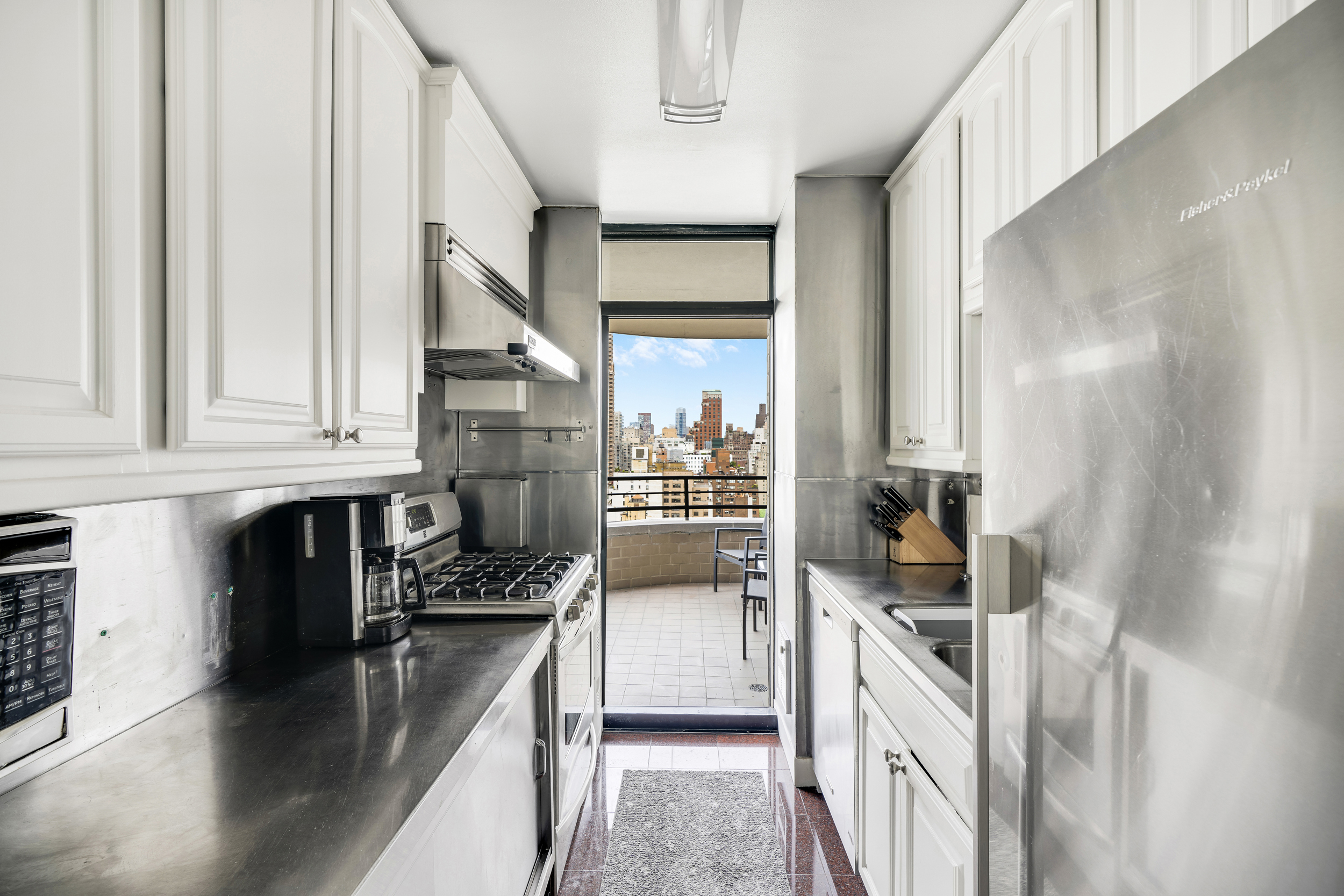 400 East 70th Street, Unit 2402 Manhattan, NY 10021 - Photo 5 of 18 a kitchen with stainless steel appliances granite countertop a refrigerator a sink and a stove
