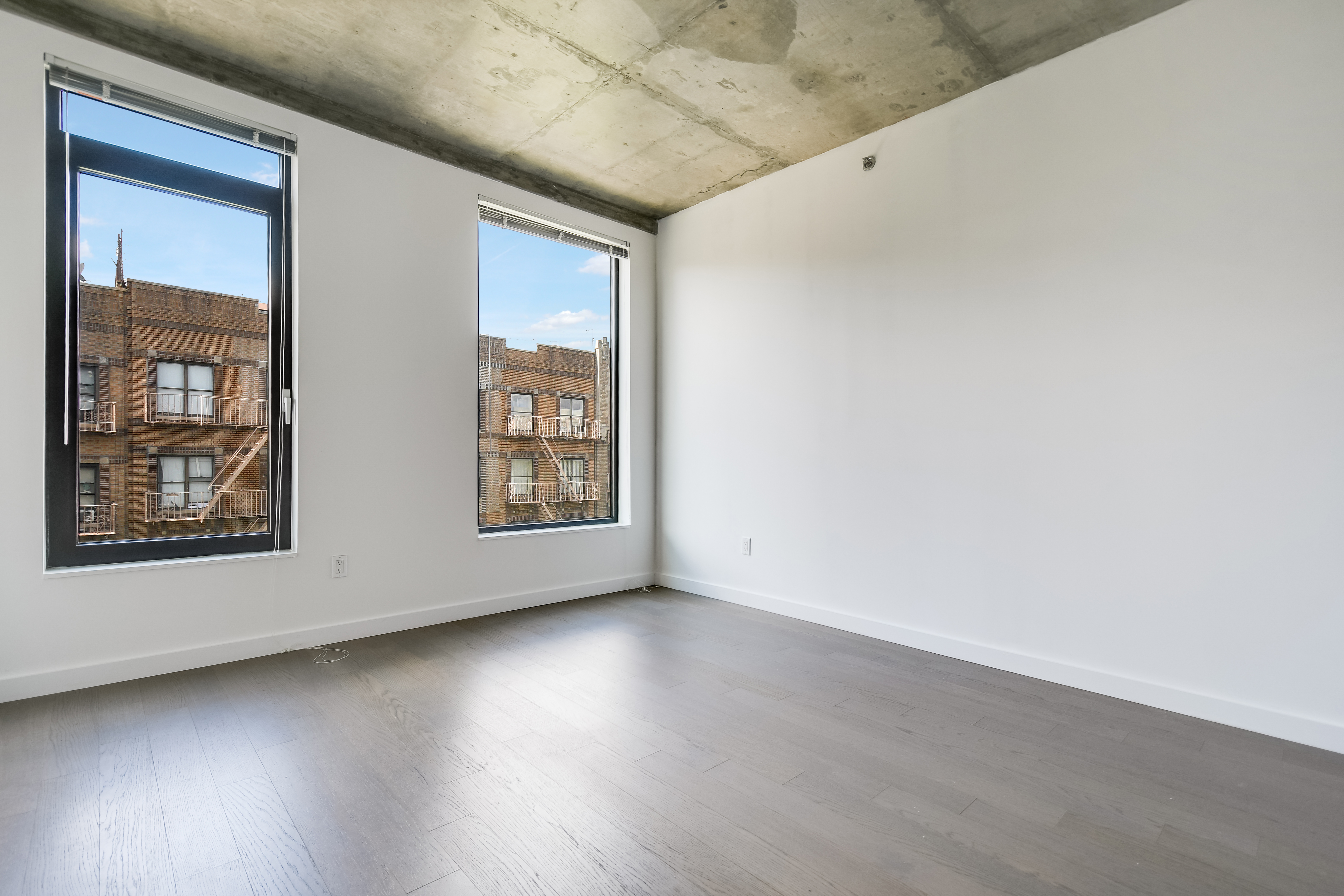 281 Union Avenue, Unit PHJ Brooklyn, NY 11211 - Photo 4 of 8 an empty room with wooden floor and windows