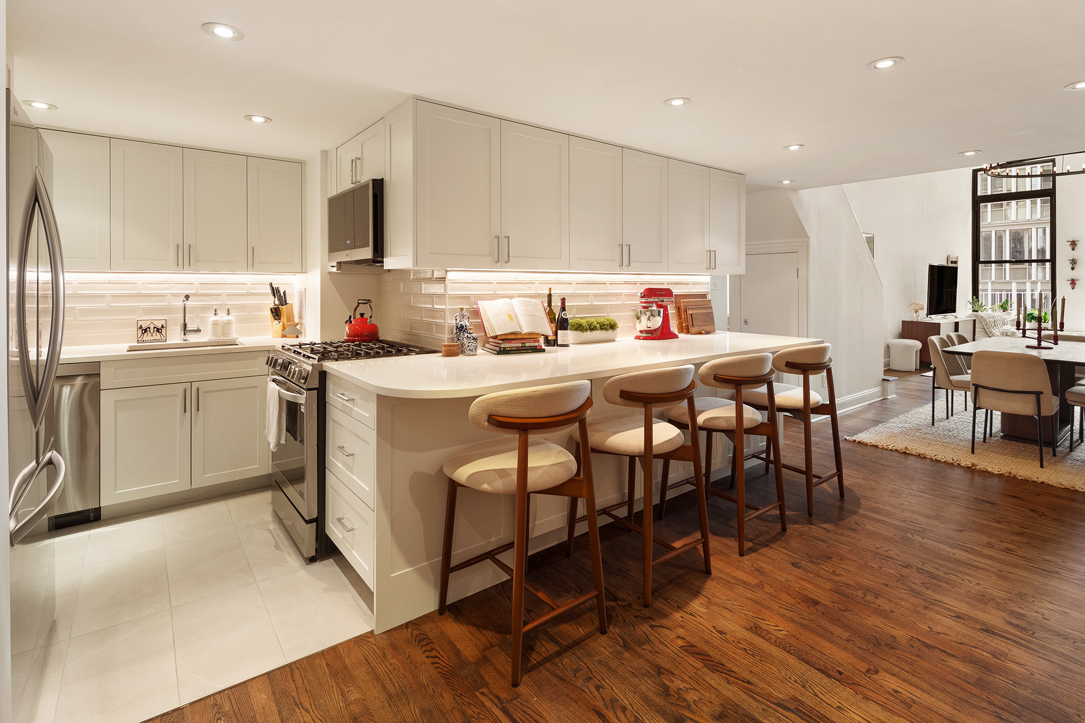 250 Mercer Street, Unit C302 Manhattan, NY 10012 - Photo 5 of 24 a kitchen with a dining table chairs wooden floor cabinets and stainless steel appliances