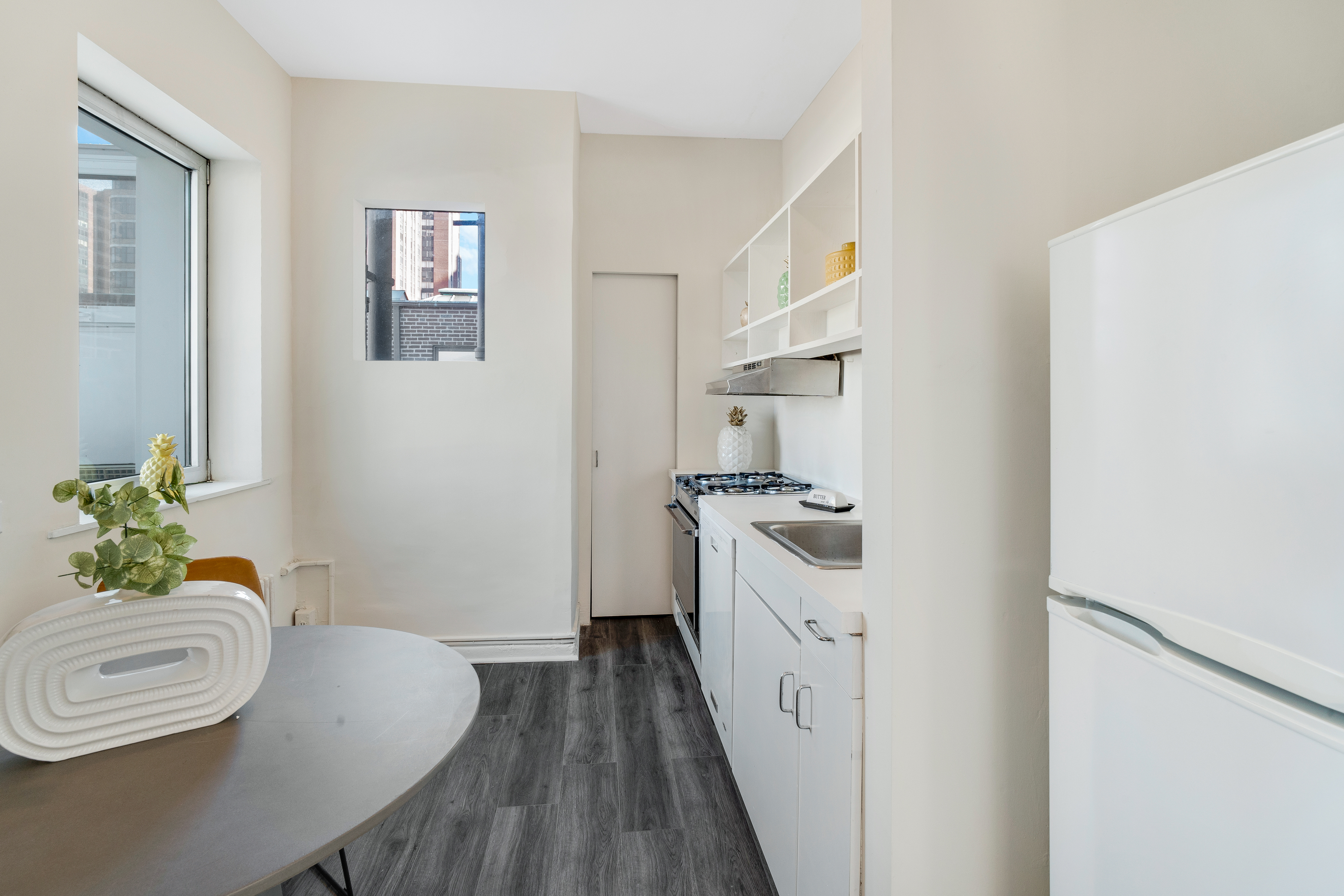 1349 Lexington Avenue, Unit PH2 Manhattan, NY 10128 - Photo 8 of 18 a kitchen with stainless steel appliances a white stove top oven a sink a dining table and chairs