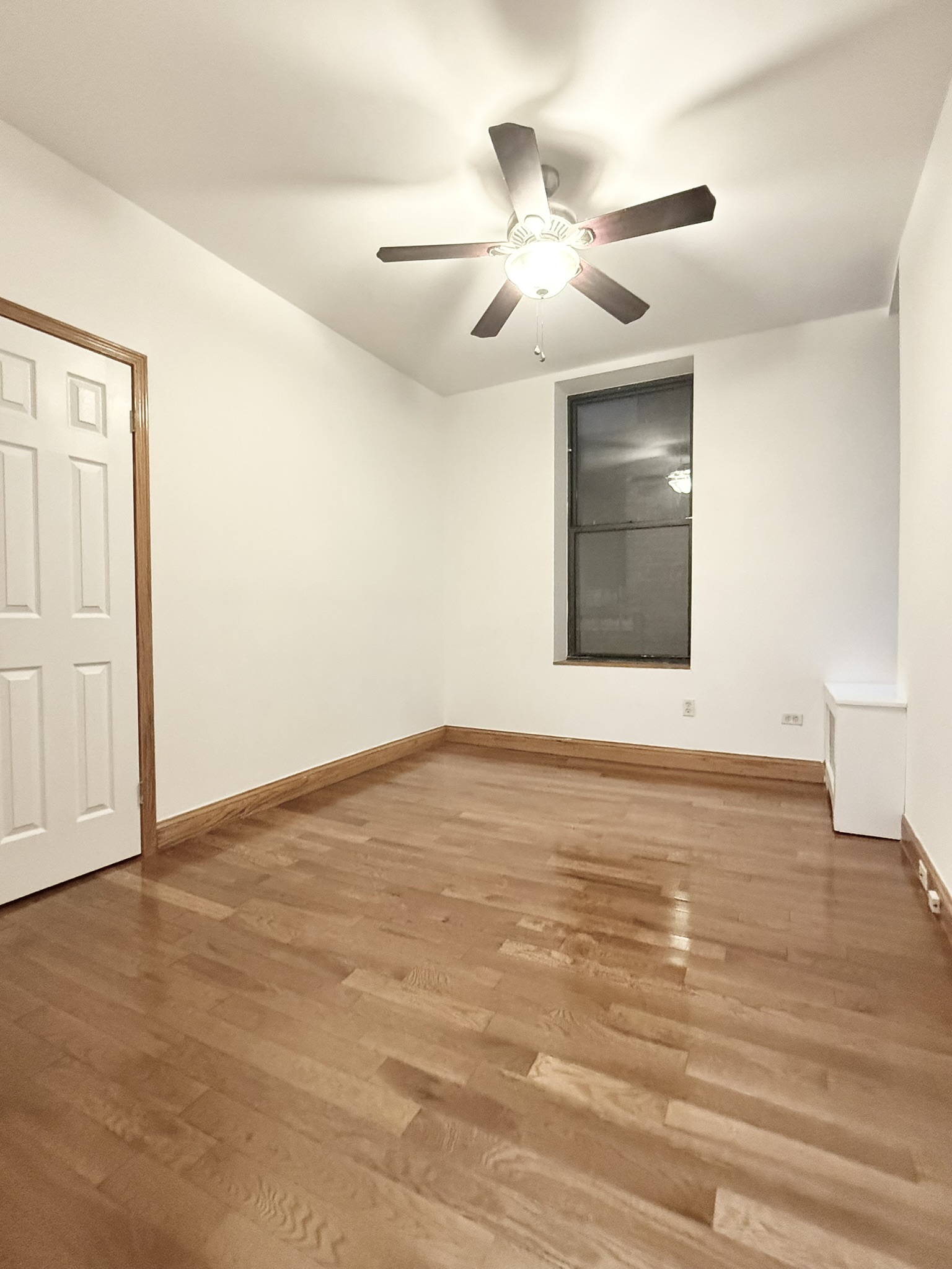 839 West End Avenue, Unit 3D Manhattan, NY 10025 - Photo 5 of 10 an empty room with wooden floor ceiling fan and windows