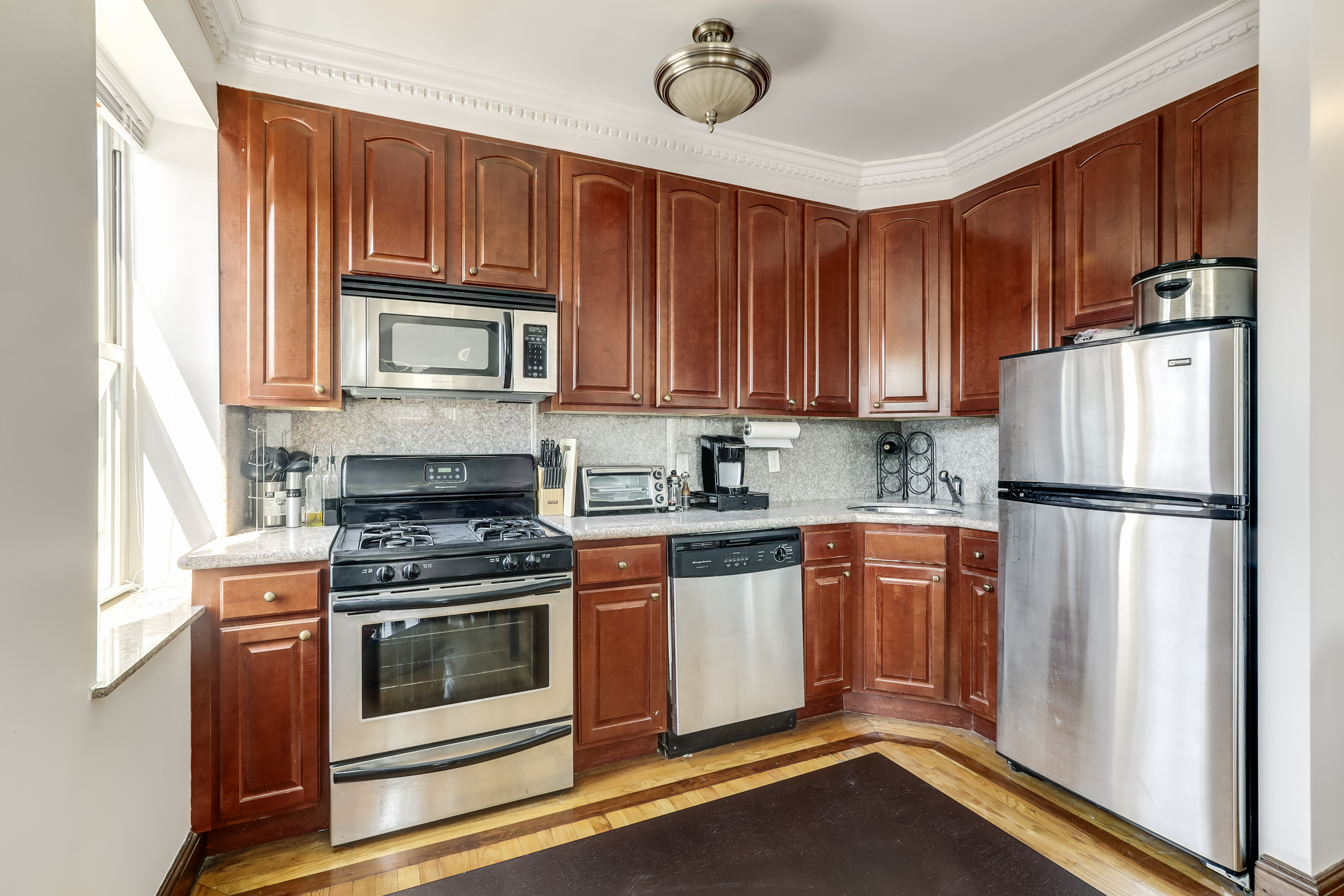 223 Smith Street, Unit 3F Brooklyn, NY 11201 - Photo 2 of 8 a kitchen with granite countertop wooden cabinets stainless steel appliances and a window