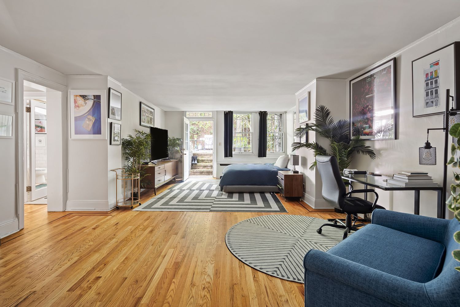 20 West 9th Street, Unit DUPLEX Manhattan, NY 10011 - Photo 6 of 10 a living room with furniture a flat screen tv and a dining table with wooden floor