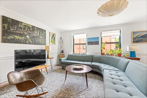 a living room with furniture a flat screen tv and a window