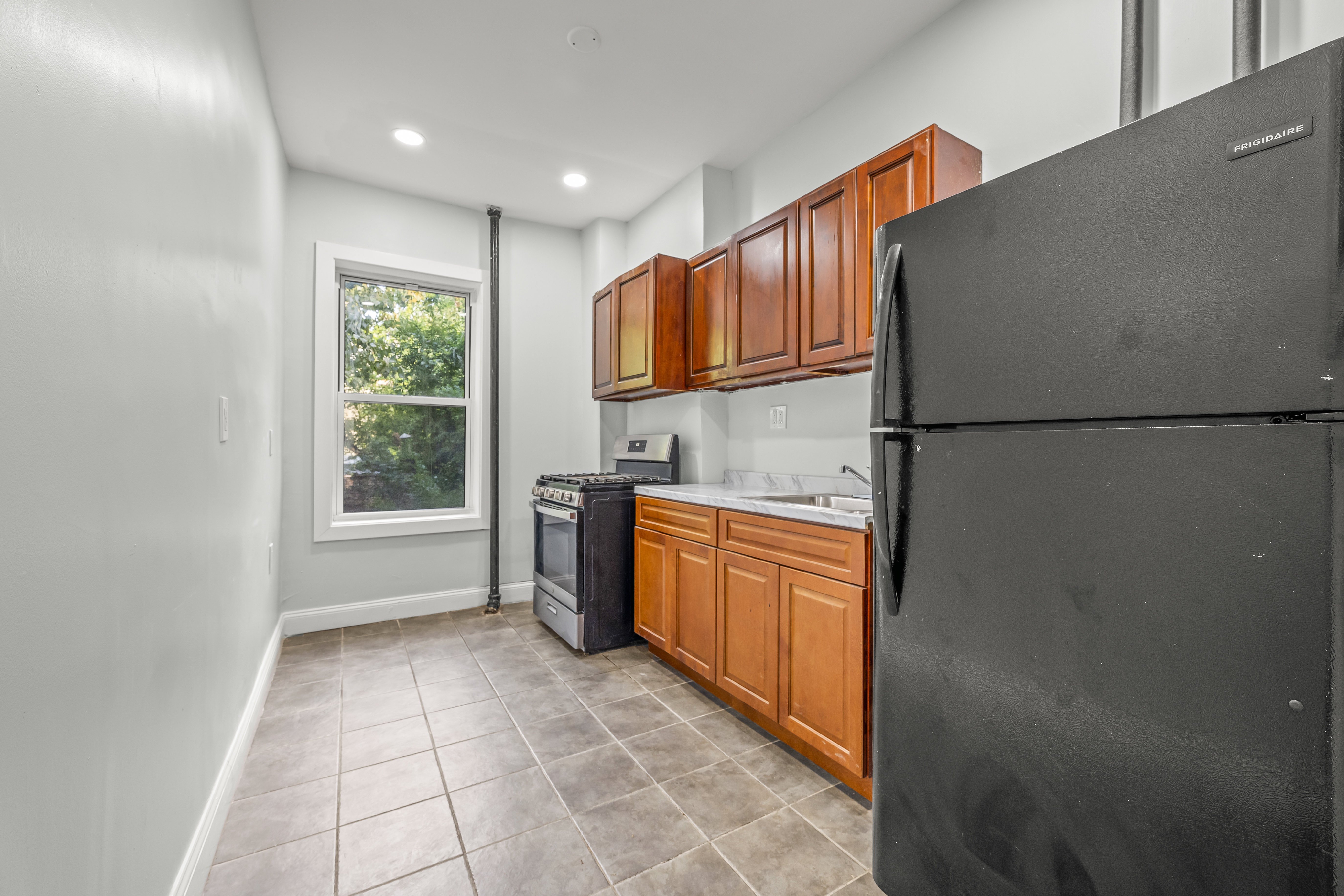 2023 Hughes Avenue Bronx, NY 10457 - Photo 3 of 63 a kitchen with stainless steel appliances granite countertop a refrigerator a sink a stove top oven and a dishwasher next to a window