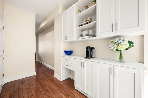 a kitchen with white cabinets and wooden floor