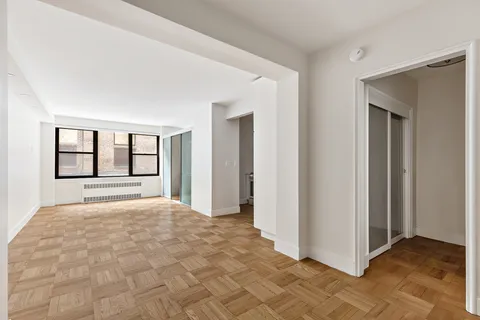 a view of an empty room with window and cabinet