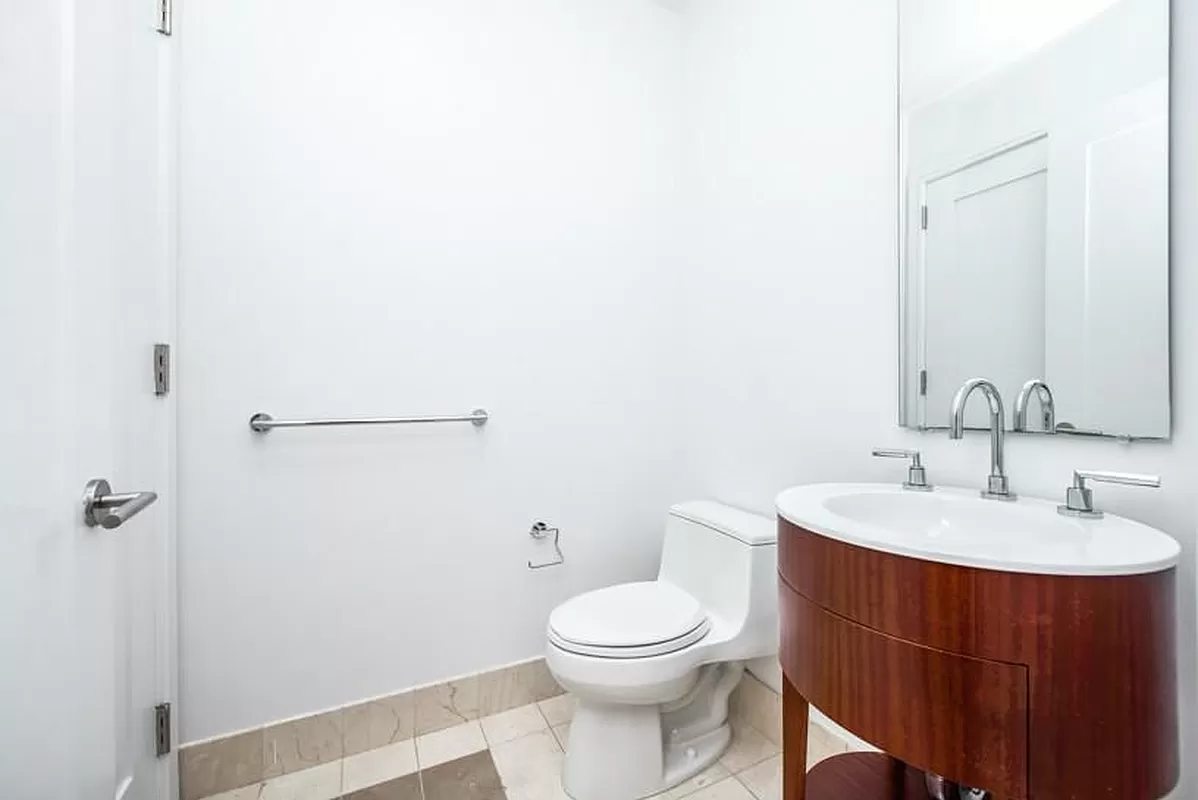 30 West Street, Unit 6B Manhattan, NY 10004 - Photo 8 of 13 a bathroom with a toilet a sink and mirror
