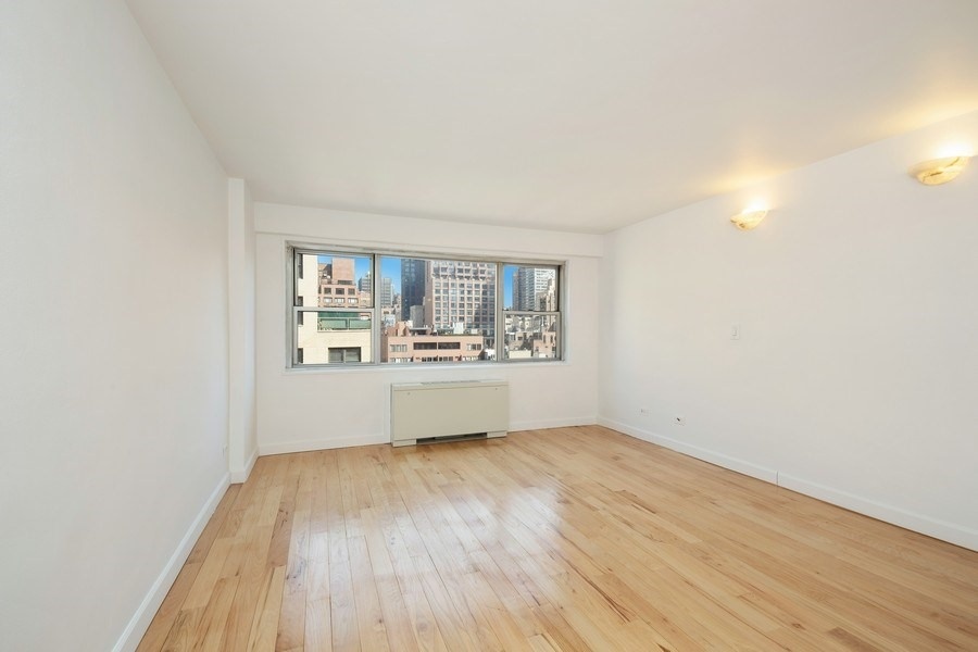 330 East 49th Street, Unit 11G Manhattan, NY 10017 - Photo 2 of 9 an empty room with wooden floor and windows