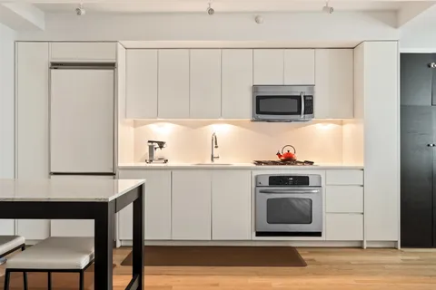 a kitchen with stainless steel appliances a stove a microwave a sink and white cabinets