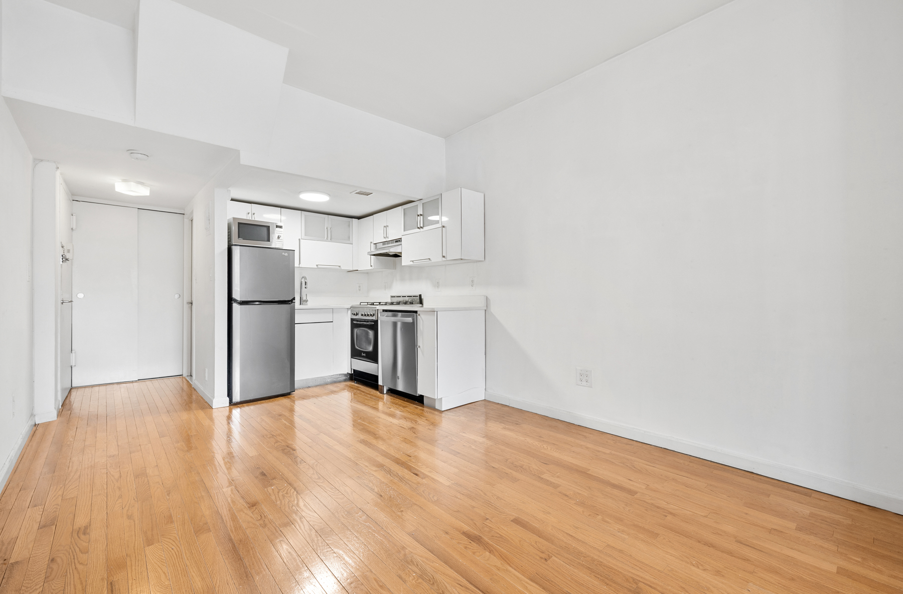 184 Thompson Street, Unit 4U Manhattan, NY 10012 - Photo 7 of 9 a view of kitchen refrigerator and wooden floor