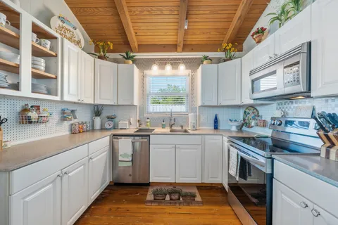 a kitchen with stainless steel appliances granite countertop a sink window and cabinets