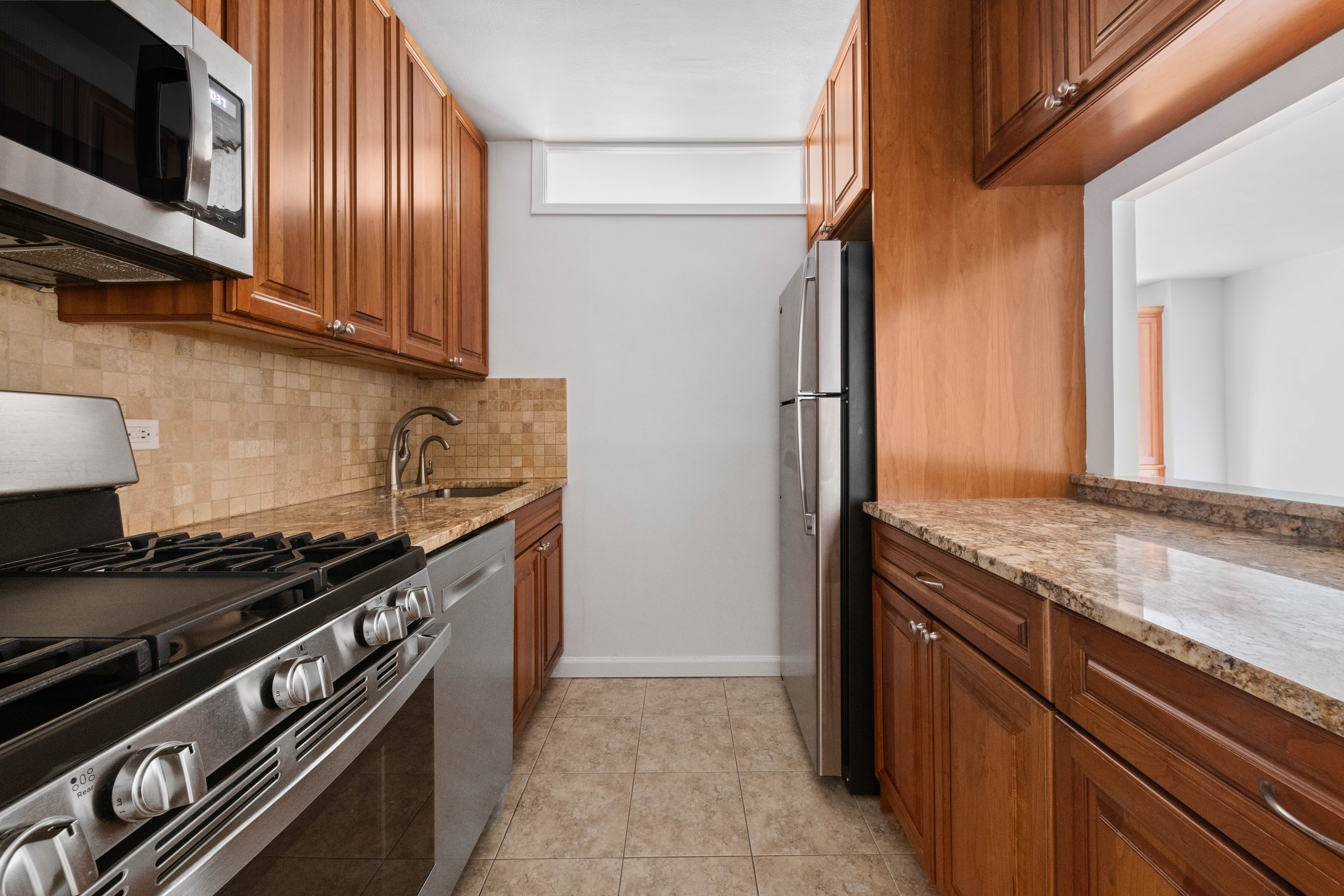 370 East 76th Street, Unit C607 Manhattan, NY 10021 - Photo 5 of 12 a kitchen with stainless steel appliances granite countertop a stove and a microwave