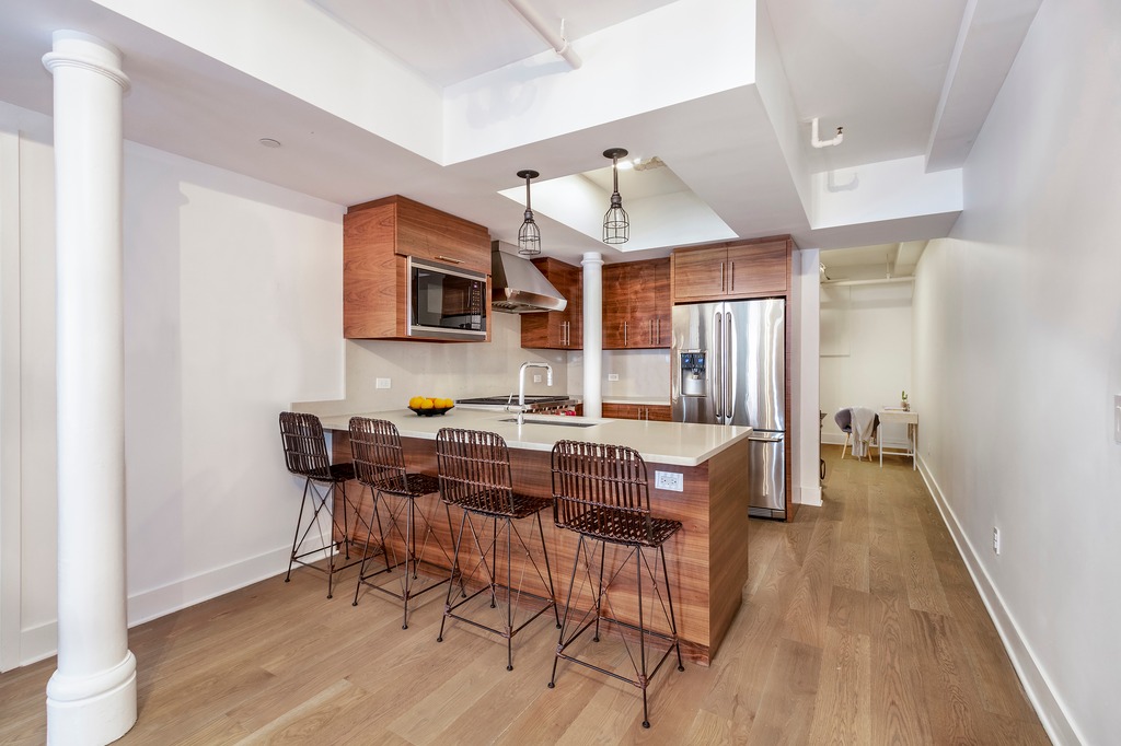 133 Mulberry Street, Unit 5A Manhattan, NY 10013 - Photo 4 of 15 a kitchen with stainless steel appliances a dining table chairs and a refrigerator