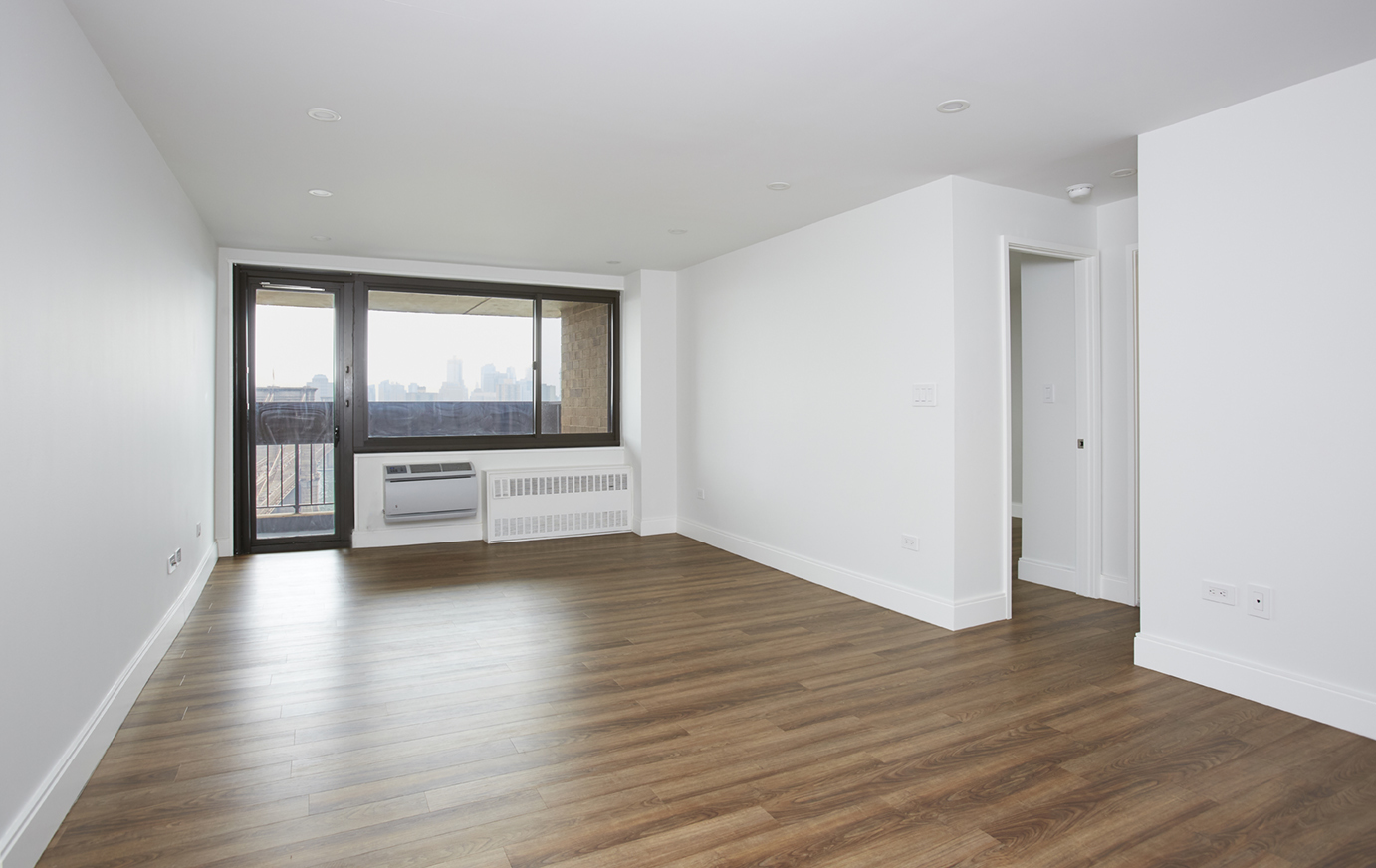 333 Pearl Street, Unit 26M Manhattan, NY 10038 - Photo 2 of 15 an empty room with wooden floor and windows