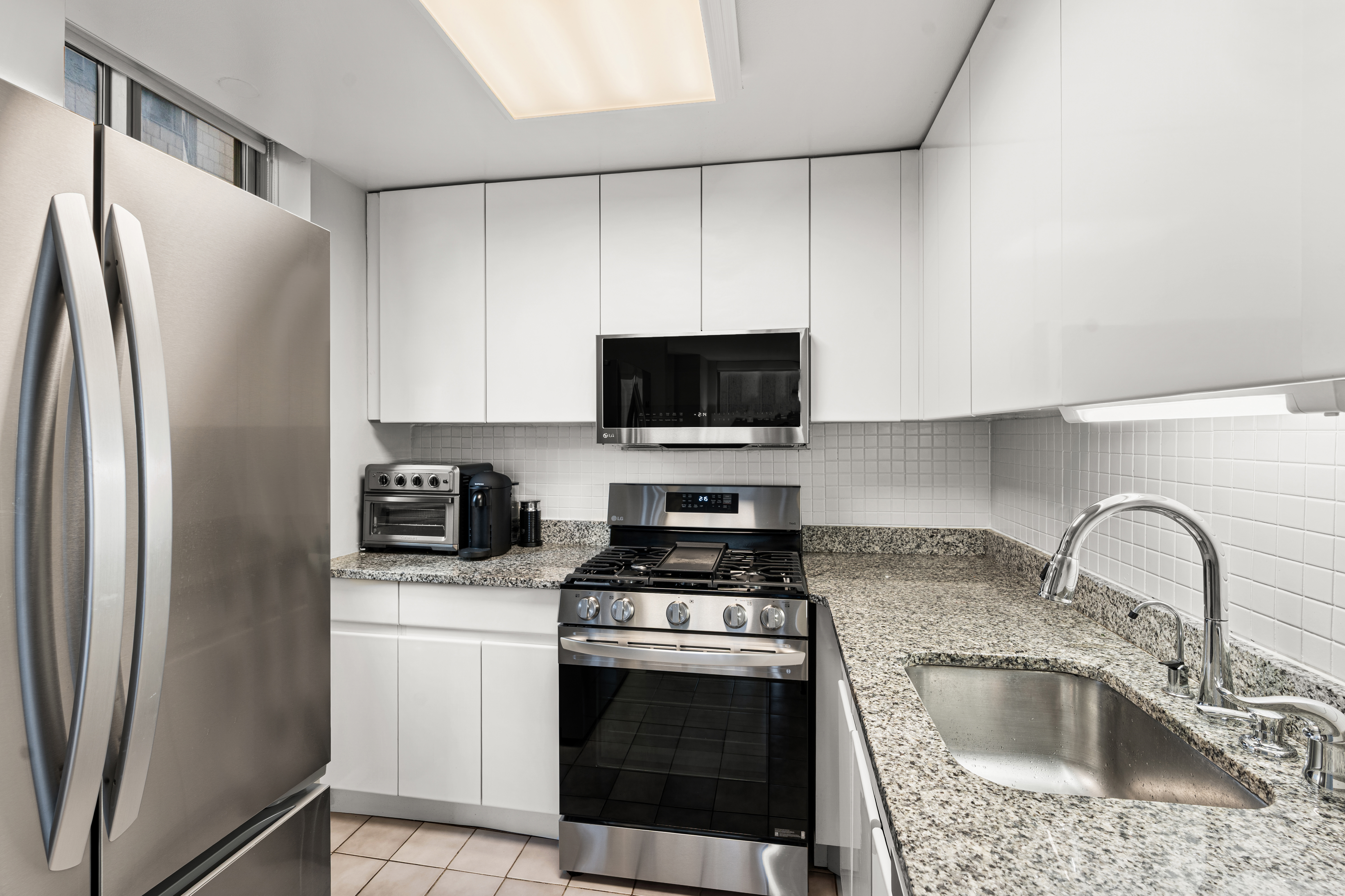 236 East 47th Street, Unit 17C Manhattan, NY 10017 - Photo 3 of 11 a kitchen with stainless steel appliances granite countertop a refrigerator stove and sink