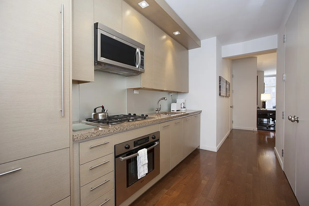 1600 Broadway, Unit 7F Manhattan, NY 10019 - Photo 5 of 7 a kitchen with stainless steel appliances granite countertop a stove a sink and a microwave