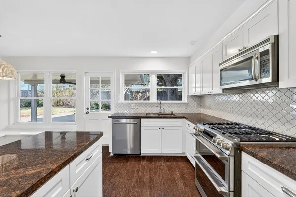 a kitchen with stainless steel appliances granite countertop a stove a sink and a microwave