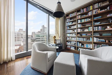 a living room with furniture a bookshelf and a large window