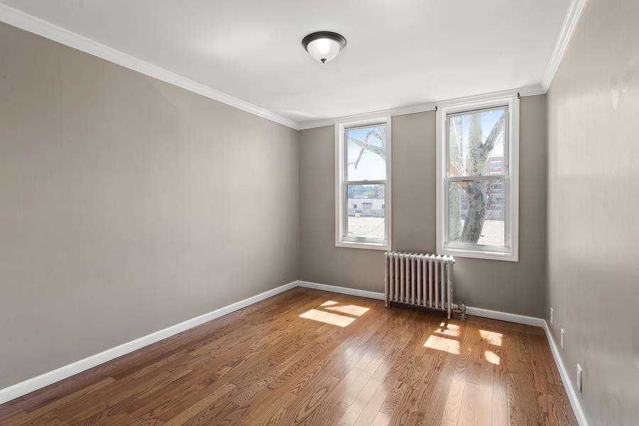 11-15 30th Drive, Unit 2F Queens, NY 11102 - Photo 3 of 6 an empty room with wooden floor and windows