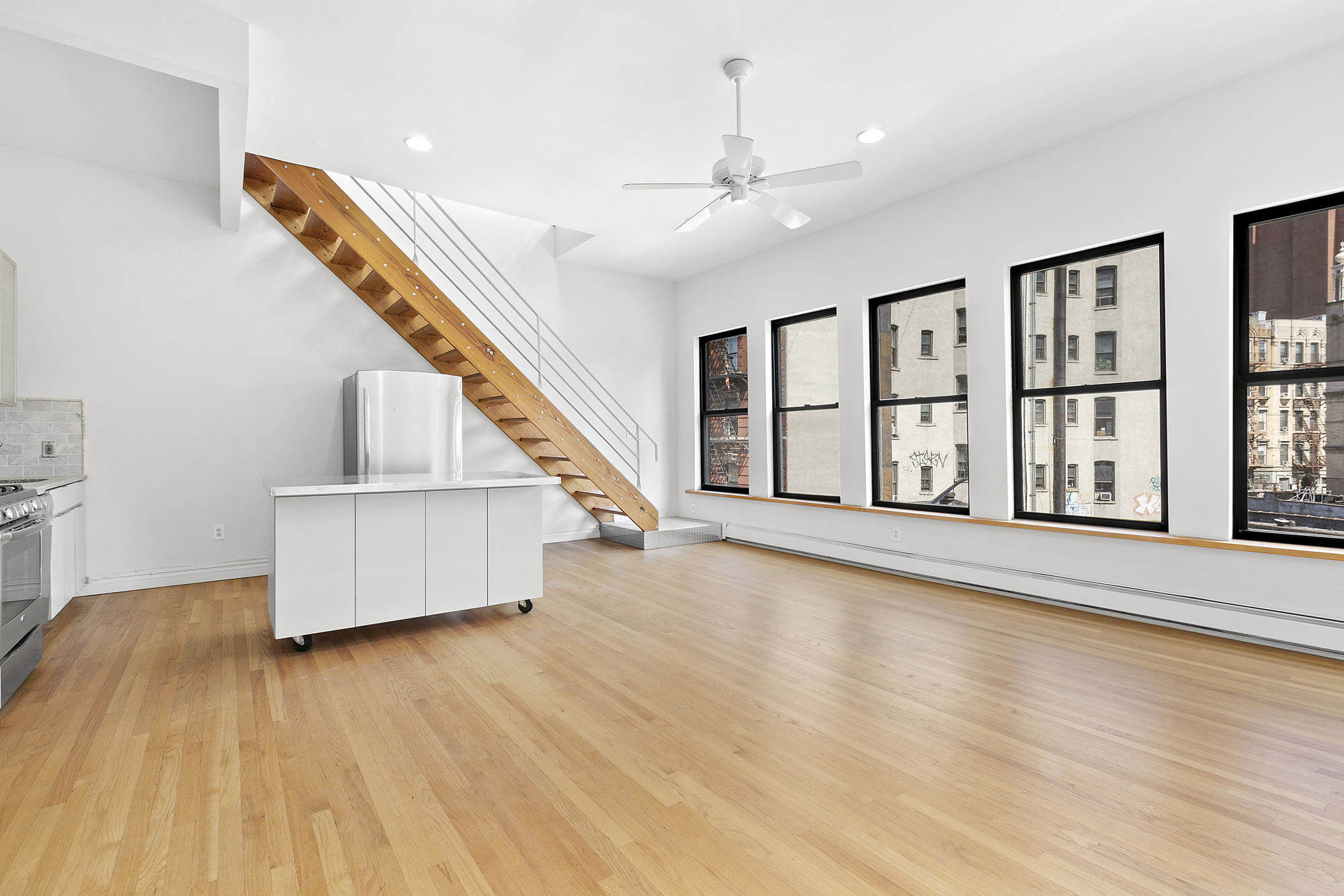 85 Division Street, Unit 4 Manhattan, NY 10002 - Photo 3 of 22 a view of an empty room with wooden floor and a window
