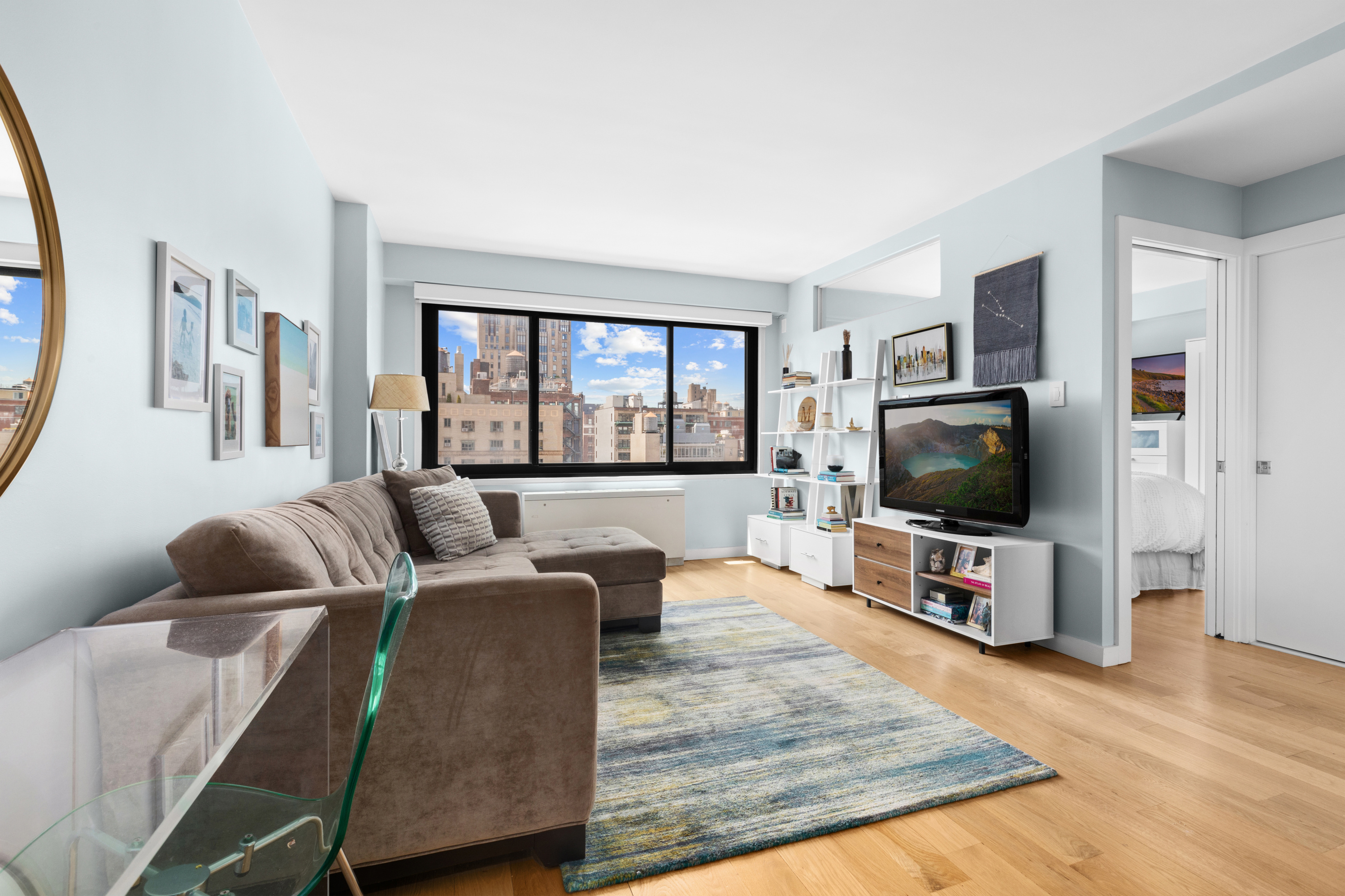 201 West 21st Street, Unit 15J Manhattan, NY 10011 - Photo 1 of 6 a living room with furniture and a flat screen tv