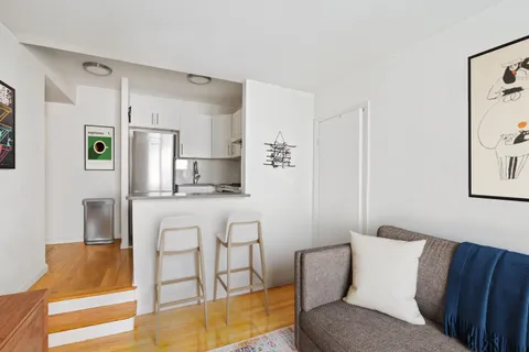 a living room with stainless steel appliances furniture and a kitchen view