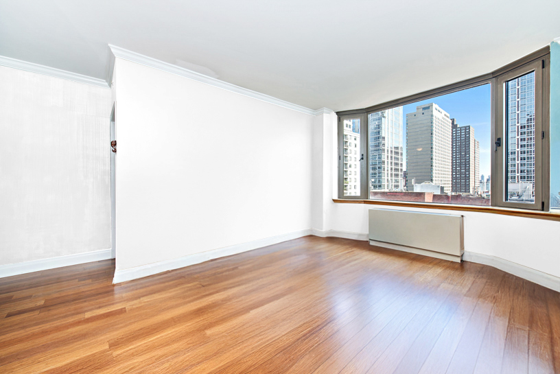 400 East 90th Street, Unit 7E Manhattan, NY 10128 - Photo 1 of 12 an empty room with wooden floor and windows