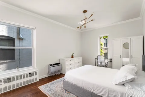 a bedroom with a bed a table and wooden floor