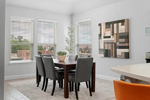 a kitchen with a dining table chairs and large windows