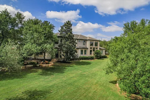 a view of a house with a garden and trees