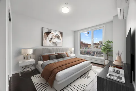 a bedroom with a bed a couch and a potted plant