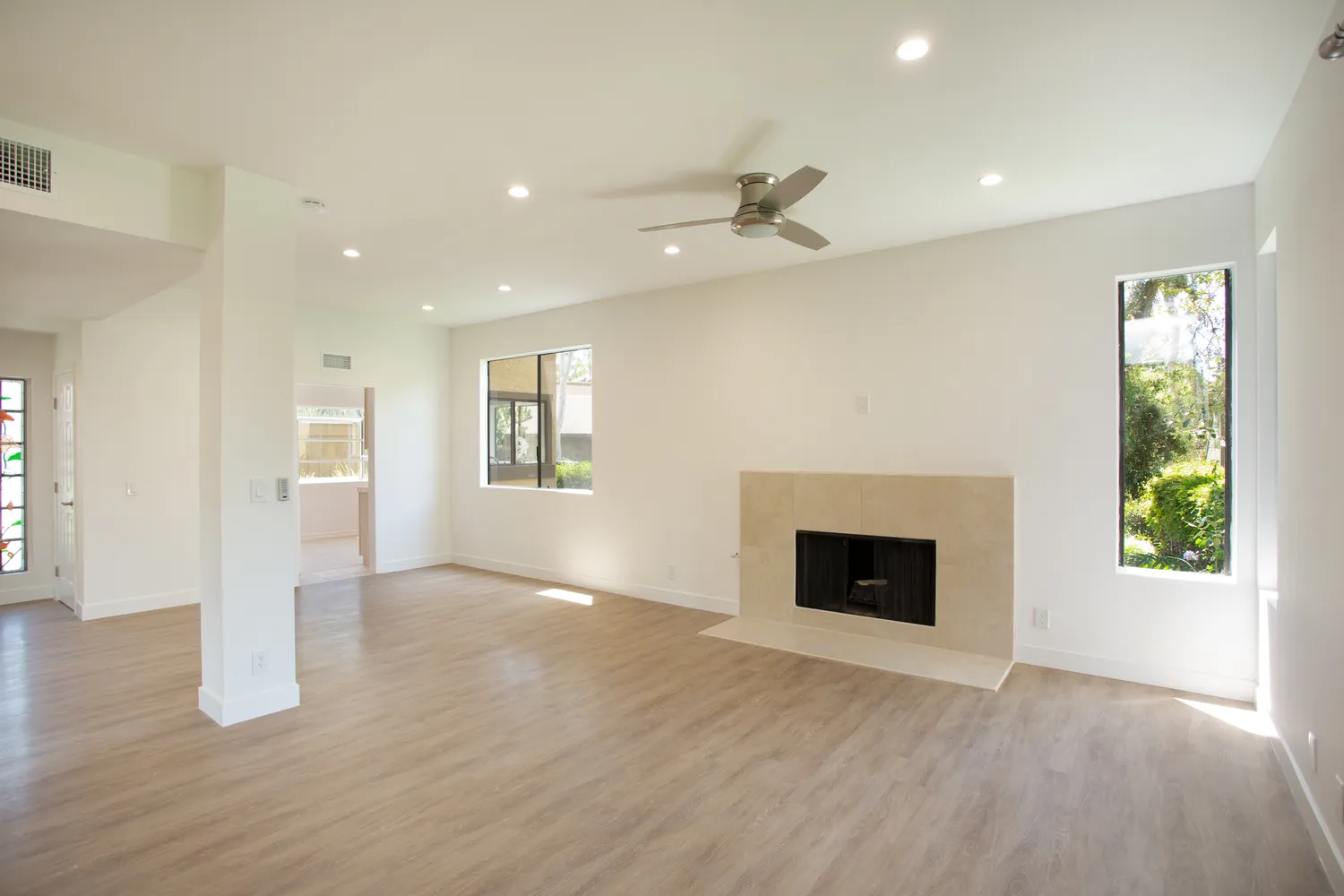 an empty room with wooden floor fireplace and windows