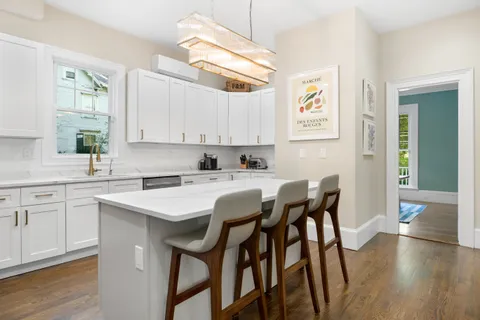 a kitchen with a dining table chairs cabinets and wooden floor