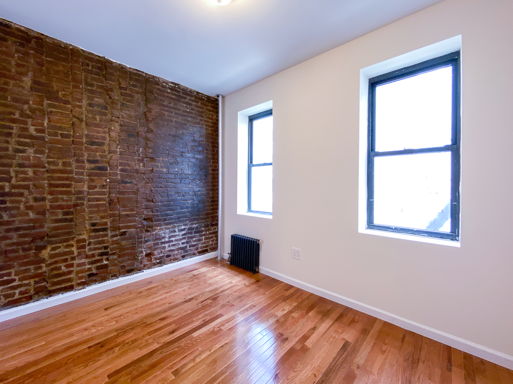319 East 25th Street, Unit 3C Manhattan, NY 10010 - Photo 3 of 12 a view of an empty room with wooden floor and a window