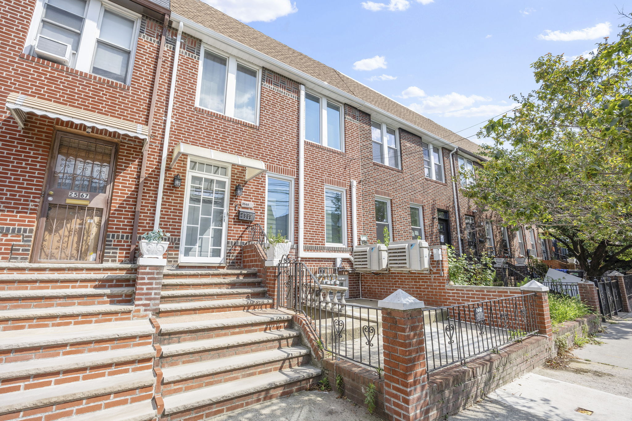 25-69 46th Street Queens, NY 11103 - Photo 2 of 33 a view of a brick house with a small yard and large trees