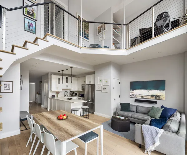 a living room with stainless steel appliances furniture a rug and a kitchen view