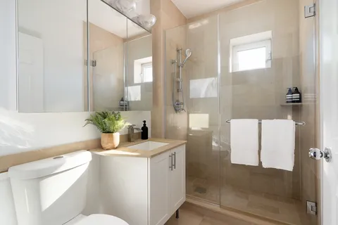 a bathroom with a granite countertop sink a toilet a mirror and shower