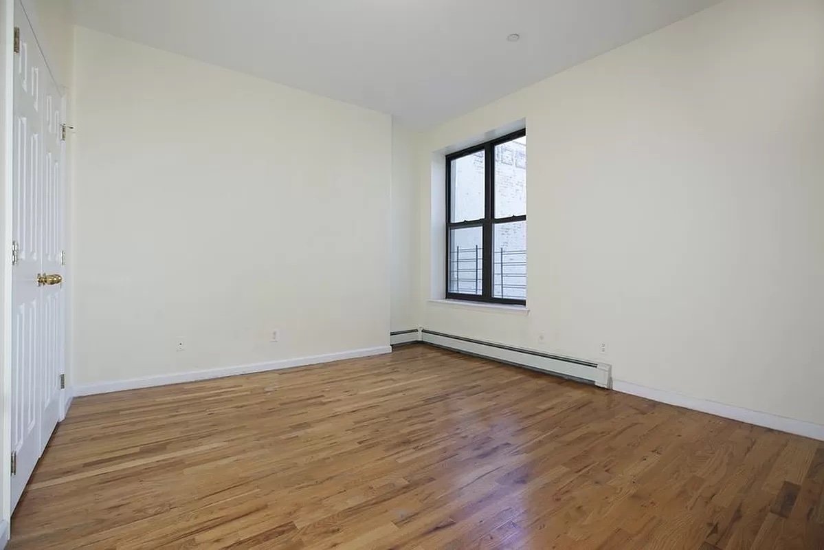 469 West 141st Street Manhattan, NY 10031 - Photo 7 of 14 an empty room with wooden floor and windows