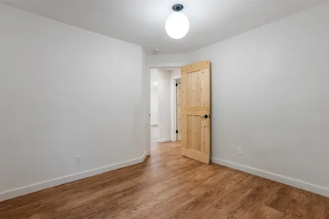 an empty room with wooden floor and mirror