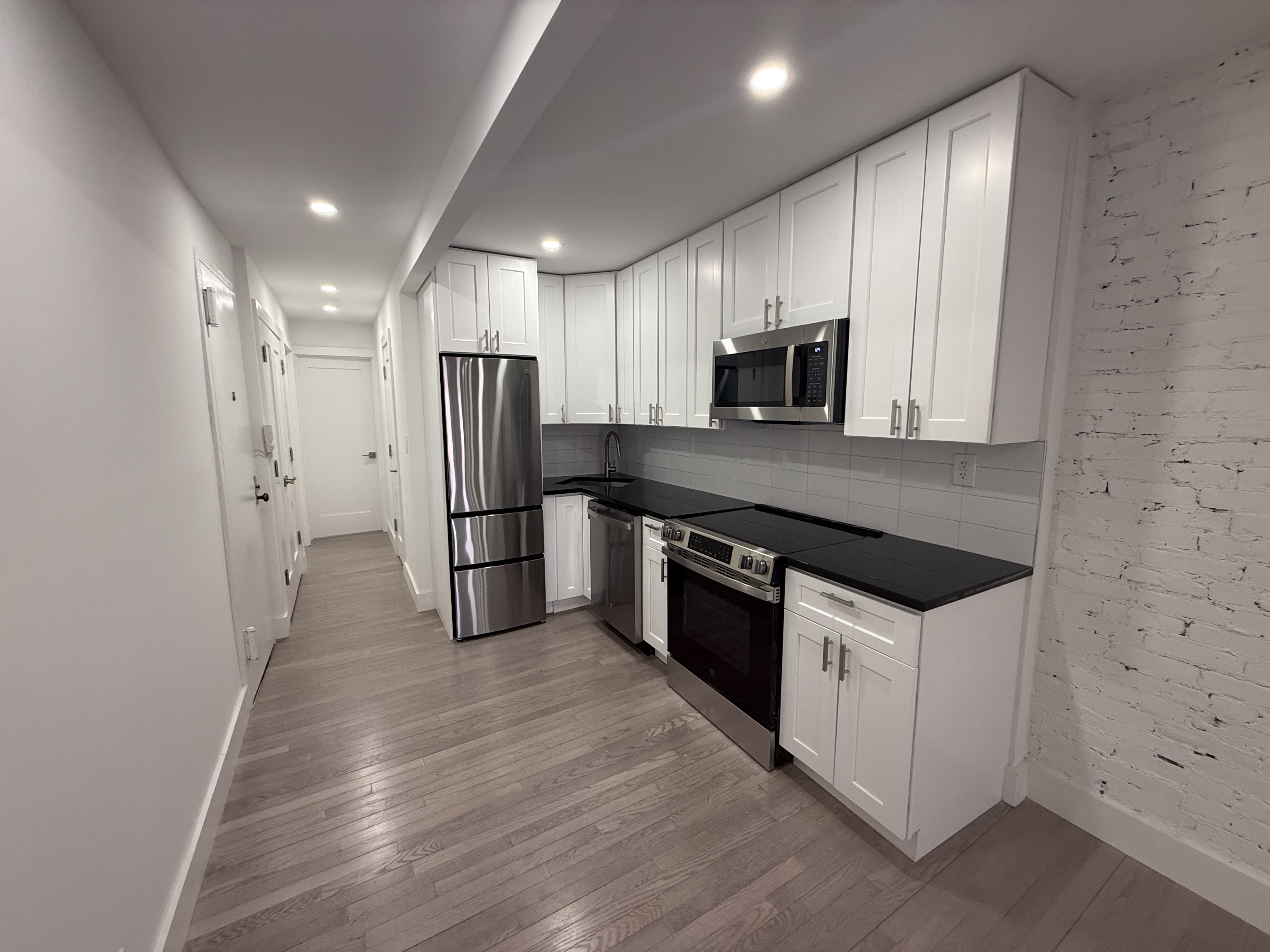 316 West 19th Street, Unit 4W Manhattan, NY 10011 - Photo 3 of 7 a kitchen with stainless steel appliances a refrigerator a sink a stove a microwave and island