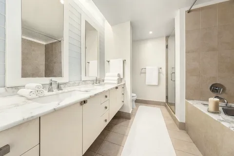 a spacious bathroom with a double vanity sink a mirror and a bathtub