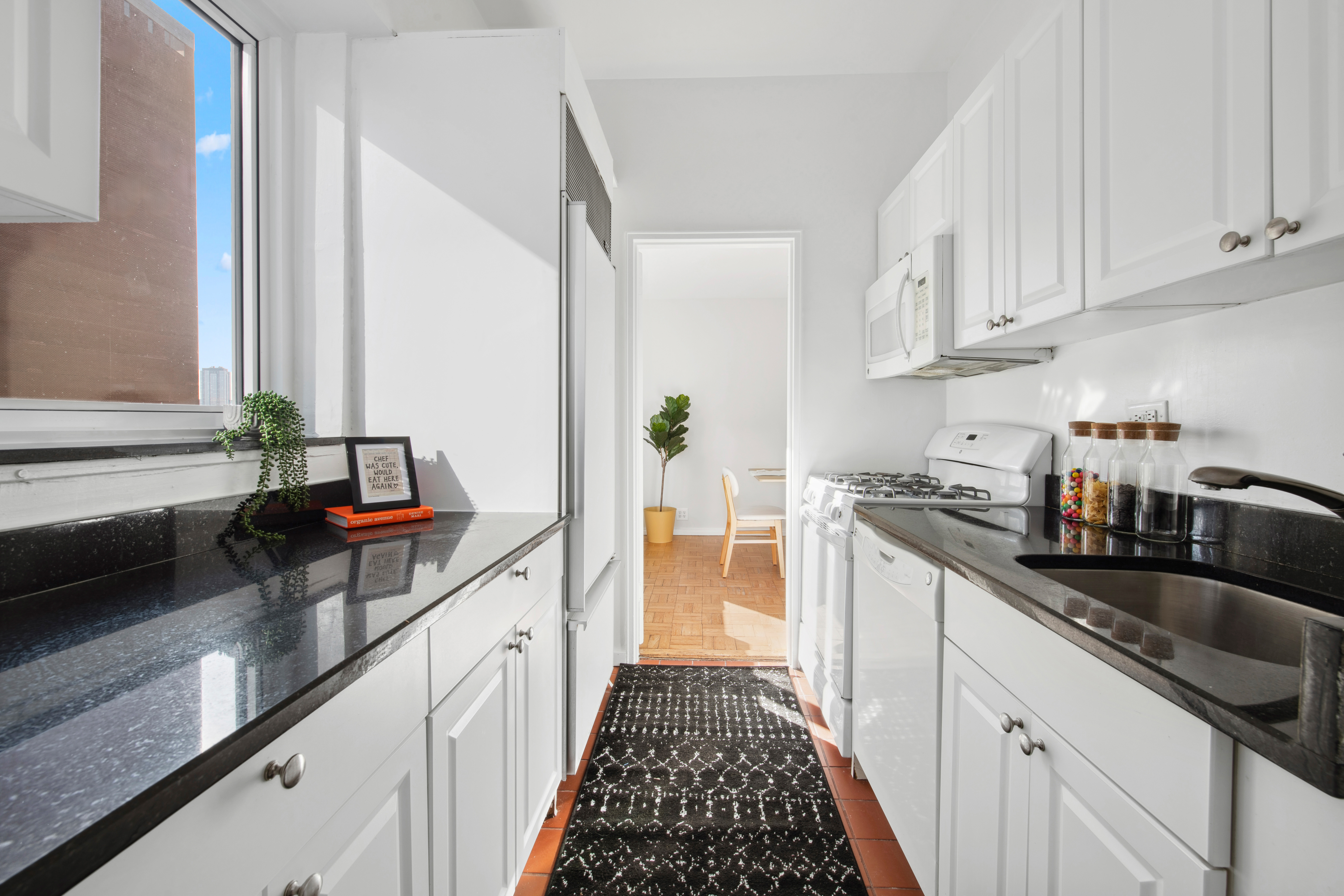 411 East 53rd Street, Unit 20A Manhattan, NY 10022 - Photo 5 of 12 a kitchen with granite countertop a sink dishwasher stove and cabinets