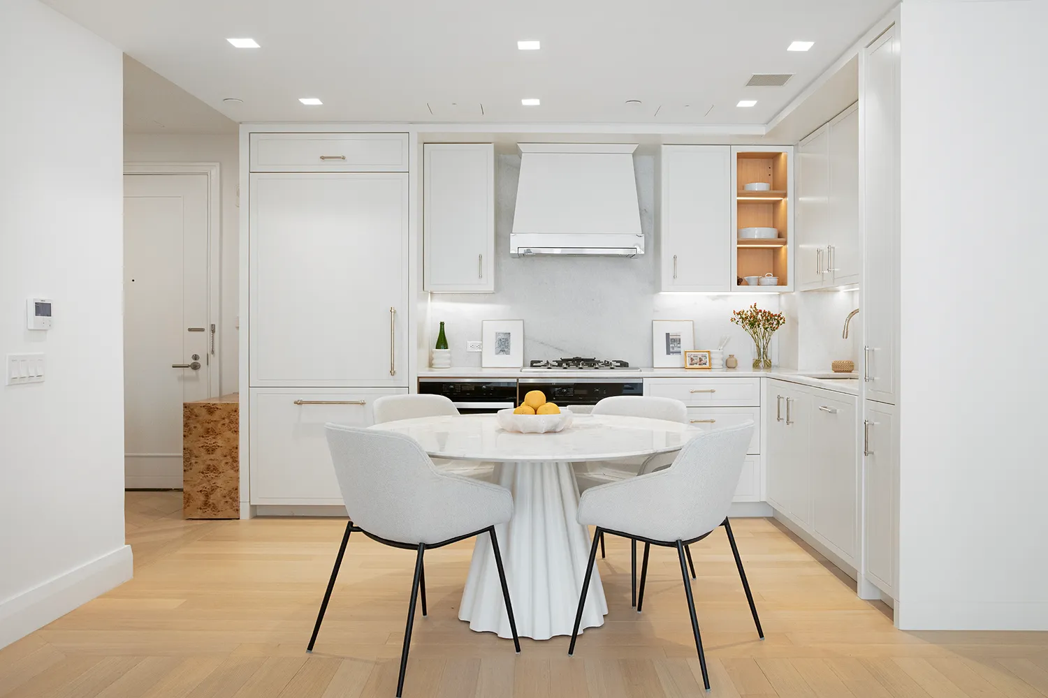 a kitchen with stainless steel appliances kitchen island granite countertop a dining table chairs and a refrigerator