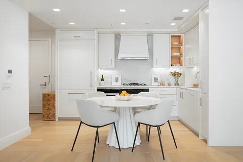 a kitchen with stainless steel appliances kitchen island granite countertop a dining table chairs and a refrigerator